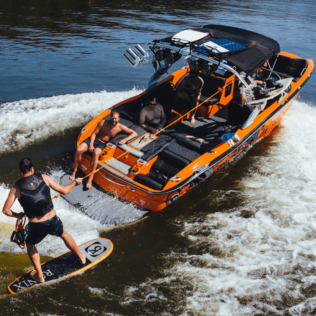 A group enjoying a wakeboarding session behind a vibrant orange speedboat.