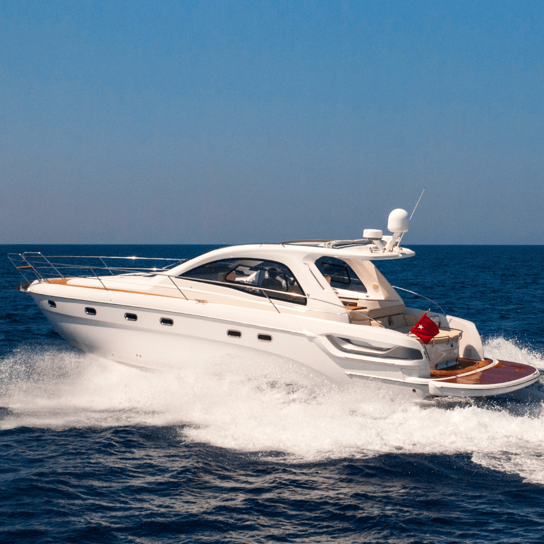 A sleek white luxury yacht cruising on the open sea under clear blue skies.